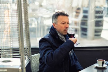 Yakışıklı adam sokak kış kafede kahve ve şarap içme. Erkek