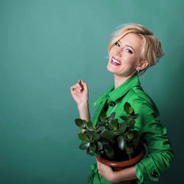 Jeune femme souriante heureuse tenant pot de fleurs avec de la plante fraîche ove — Photo