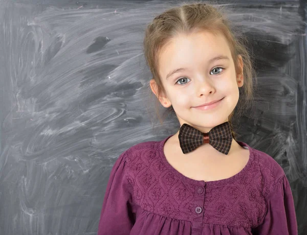 Nettes kleines Mädchen, das neben der Tafel steht und glücklich lächelt. bea — Stockfoto