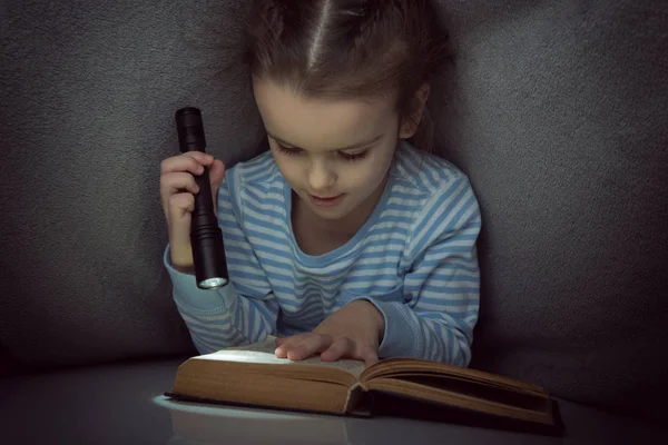 Meisje het lezen van sprookjes boek onder de dekens aan de vooravond — Stockfoto