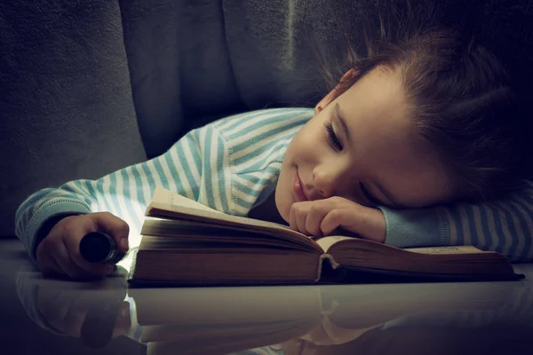 Little girl reading fairy tales book under the covers at the eve — Stock Photo, Image