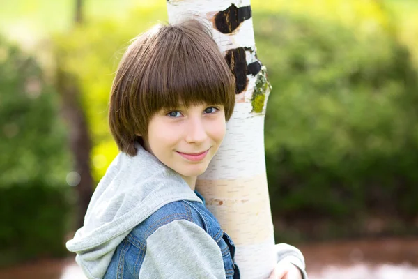 Портрет красивого мальчика на улице. Мальчик-подросток ближе к березе в спрее — стоковое фото