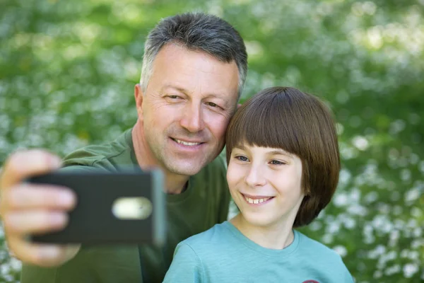 Padre e hijo tomando fotos con smartphone juntos al aire libre. Fa —  Fotos de Stock