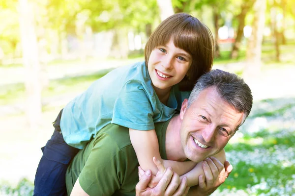 Retrato del padre con su hijo divirtiéndose en el parque de verano. Cerdito. —  Fotos de Stock