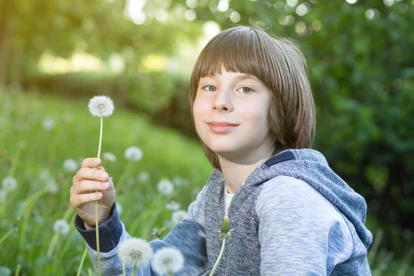 Мальчик с одуванчиком над размытой зеленой травой, летняя природа outdoo — стоковое фото