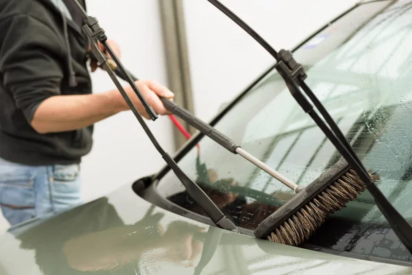 Car washing. Man cleaning car using high pressure water and brus