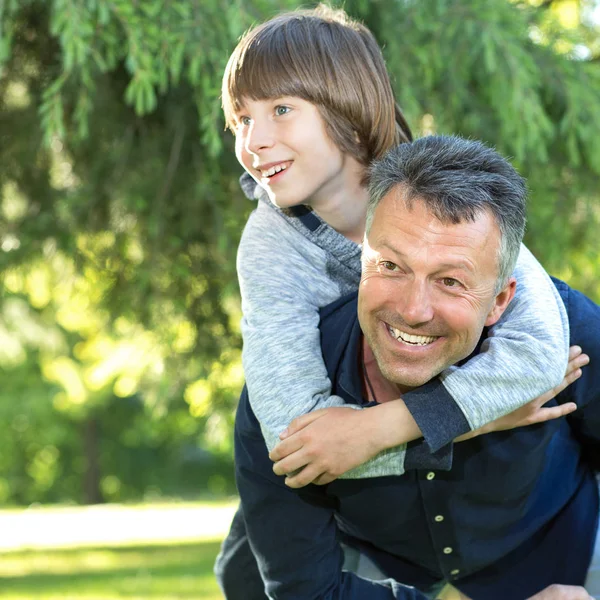 Portret van vader met zijn zoon plezier in zomer park. Piggy — Stockfoto