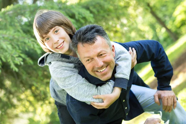 Retrato del padre con su hijo divirtiéndose en el parque de verano. Cerdito. —  Fotos de Stock