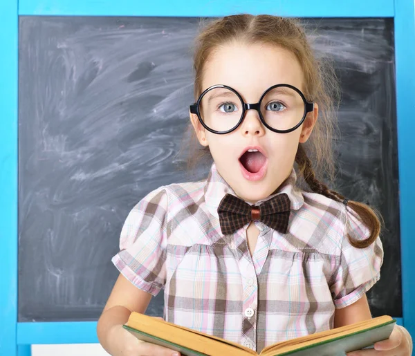 Mignon liitle fille debout près tableau noir dans drôles de grandes lunettes un — Photo