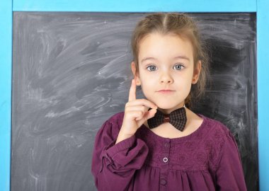 Şirin liitle kız Blackboard ve mutlu gülümseyerek ayakta. Bea