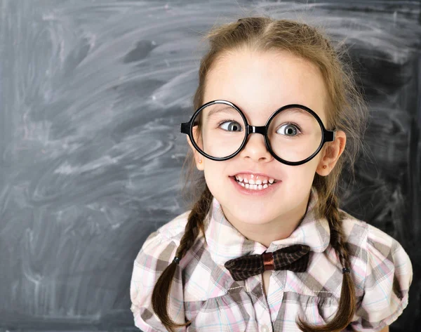 かわいい面白い liitle 女の子大きなメガネで黒板の近くに立って、 — ストック写真