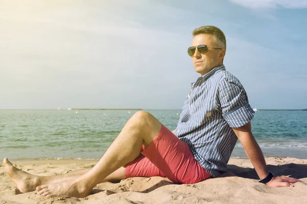 El hombre está tomando el sol en la costa del mar, naturaleza de verano al aire libre. Retrato — Foto de Stock