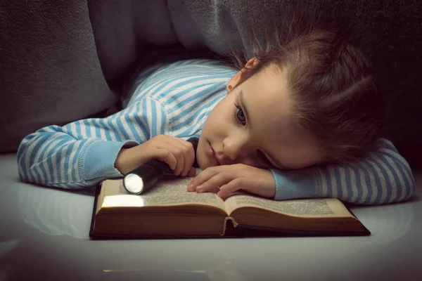 Niña leyendo cuentos de hadas libro bajo las cubiertas en la víspera —  Fotos de Stock