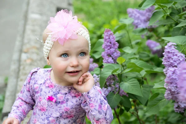 Krásná holčička voní fialovými květy na jaře parku. Dítě — Stock fotografie