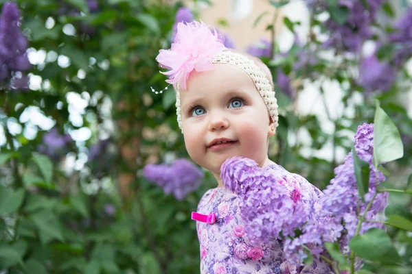 Hermosa niña feliz sonriendo sobre flores lila en primavera —  Fotos de Stock