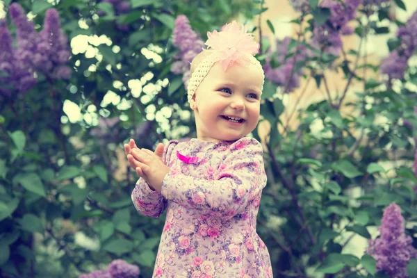 Krásná holčička šťastný úsměv a tleská rukama nad lil — Stock fotografie