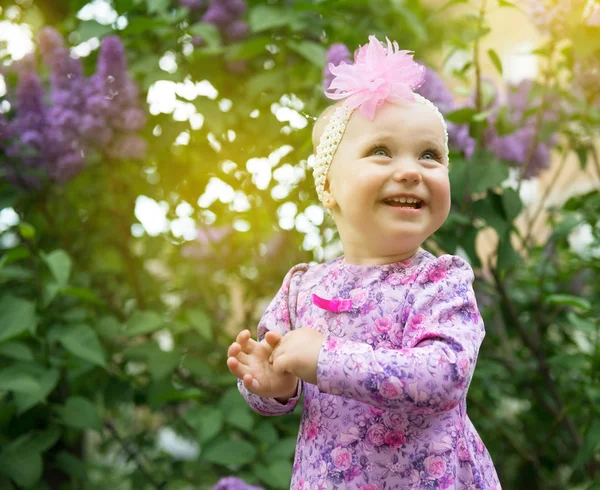 Krásná holčička šťastný úsměv a tleská rukama nad lil — Stock fotografie