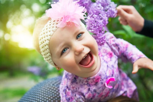 Mooi meisje speelt met moeder met lila bloemen in spr — Stockfoto