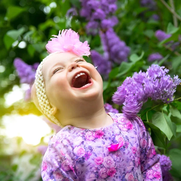 Hermosa niña jugando en el parque de primavera, flores lila gard —  Fotos de Stock