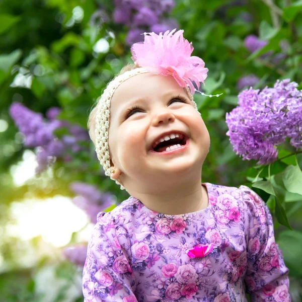 Hermosa niña jugando en el parque de primavera, flores lila gard —  Fotos de Stock