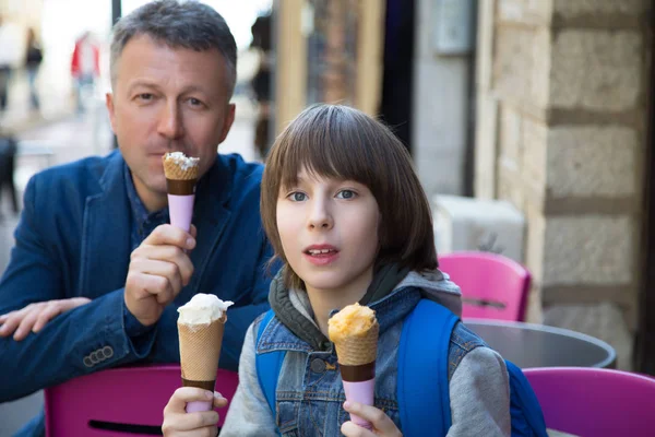Father and son eating ice-cream in street cafe, family lifestyle