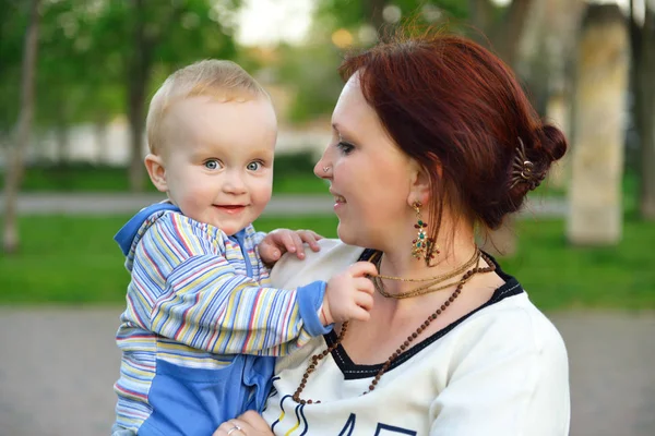 Ευτυχισμένη μητέρα κρατώντας το αξιολάτρευτο μικρό γιο. Οικογένεια υπαίθρια λέι — Φωτογραφία Αρχείου