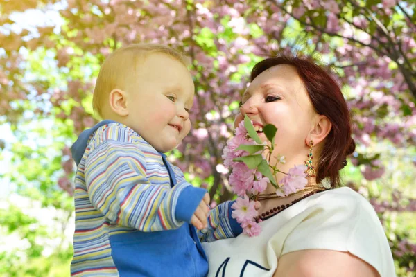 Mãe feliz segurando seu filho adorável. Família lei ao ar livre — Fotografia de Stock