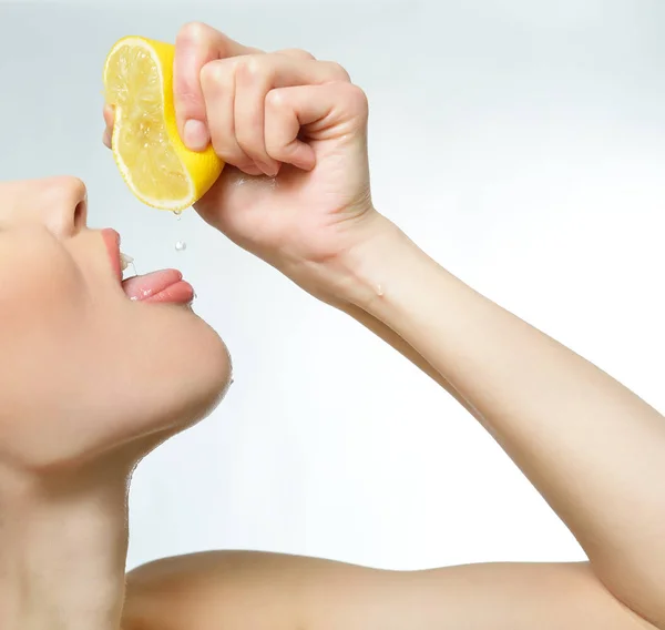 Молодая привлекательная девушка позирует в студии с лимоном. Молодые люди — стоковое фото