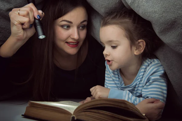 Menina e sua mãe lendo contos de fadas livro sob o co — Fotografia de Stock