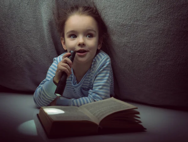 Μικρό κορίτσι ανάγνωση παραμυθιών βιβλίο κάτω από τα σκεπάσματα την παραμονή — Φωτογραφία Αρχείου