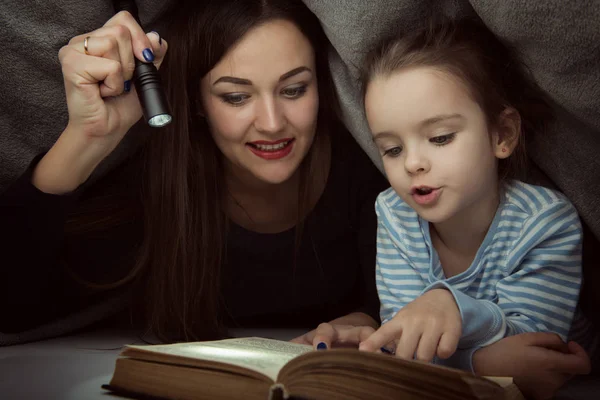 Niña y su madre leyendo cuentos de hadas libro bajo el co —  Fotos de Stock