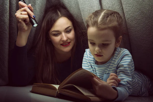 Petite fille et sa mère lisant le livre de contes de fées sous le co — Photo