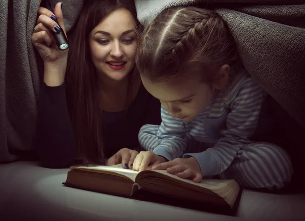 Petite fille et sa mère lisant le livre de contes de fées sous le co — Photo