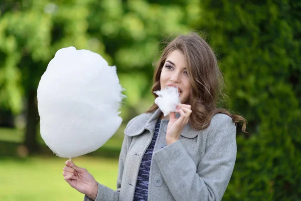 Giovane bella ragazza godendo dolce zucchero filato in primavera verde — Foto Stock