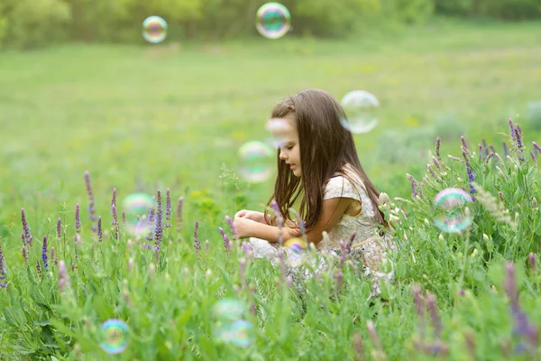 Cute little girl on a forest glade among lush vegetation and aro — Stock Photo, Image