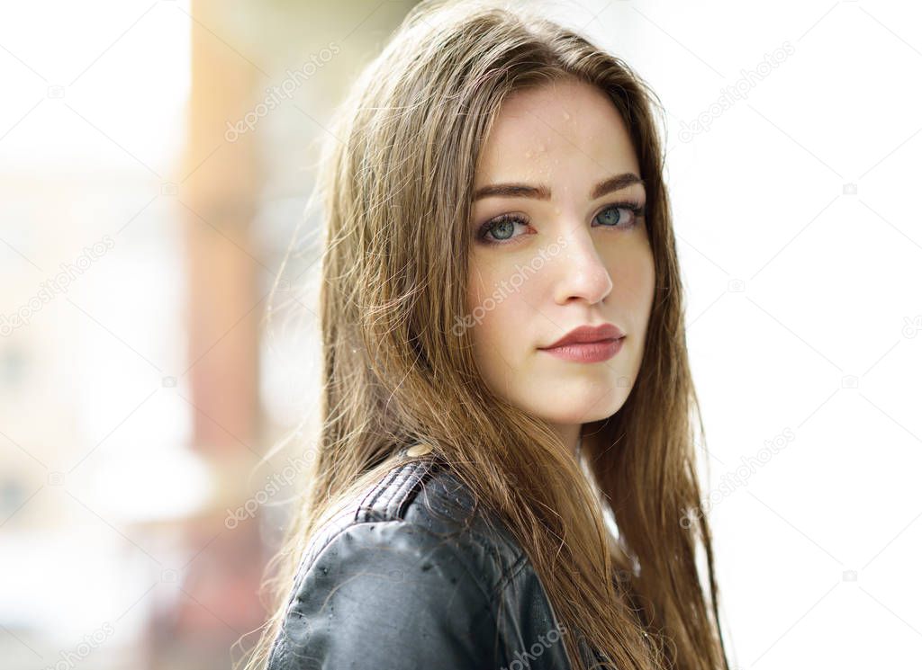 Young attractive woman standing in the rain directing her face t