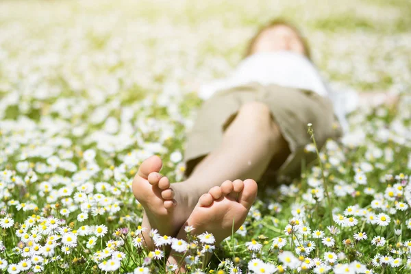 Nohy dítěte v daisy closeup zobrazit. Bosých chlapec. Malý chlapec lyi — Stock fotografie