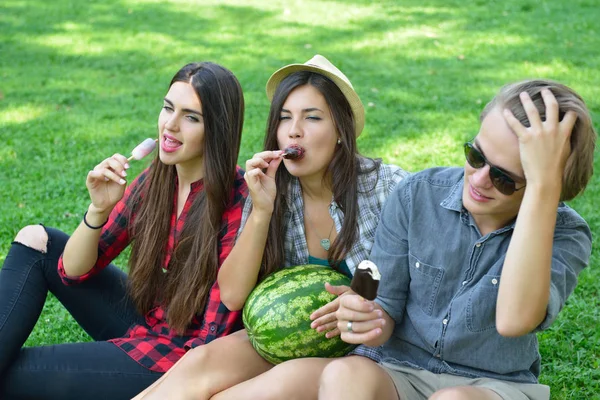 Young man and women eating chocolate ice-cream and watermelon ou — Stock Photo, Image