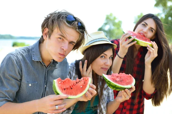 Happy friends eating watermelon on the beach. Youth lifestyle. H