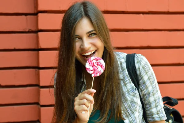 Bella ragazza ha divertimento e leccare caramelle dolci all'aperto contro r — Foto Stock