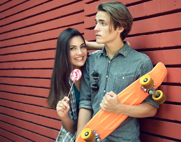 Young boy with skateboard and girl with candy having fun outdoor — Stock Photo, Image