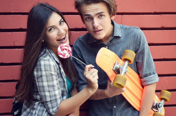 Young boy with skateboard and girl with candy having fun outdoor — Stock Photo, Image