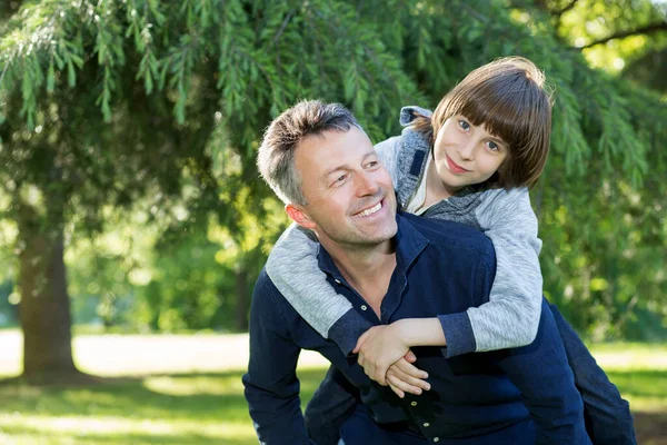 夏の公園で楽しんでいる彼の息子と父親の肖像画 ピギーバック 家族の楽しみ パパの夏の自然屋外で遊んで幸せな男の子 子育て — ストック写真