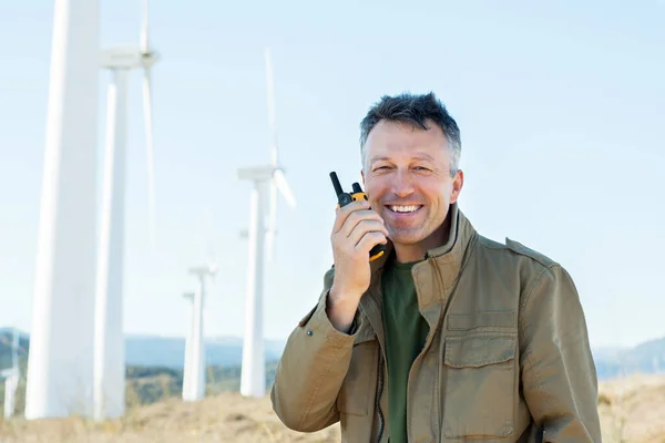 Man talking with portable radio transmitter outdoor over the wind turbines, image toned. Windmill generators. Wind power generators.