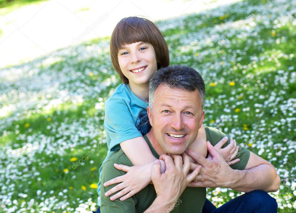 Portrait of father with his son having fun in summer park. Piggyback. Family fun. Happy boy playing with dad summer nature outdoor