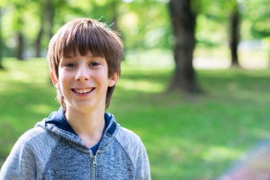 Şirin, mutlu, yakışıklı bir çocuk, açık hava portresi. Yaz parkında gülümseyen genç bir çocuk.. 