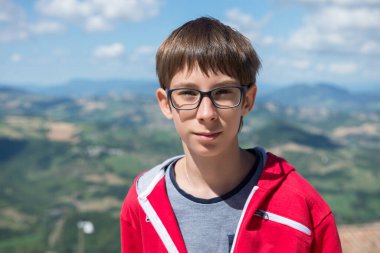 San Marino 'nun dışındaki kameraya bakan gözlüklü genç bir çocuk. Görüş, görme, görme, diopterler, gözlük, gözlük, sağlık.