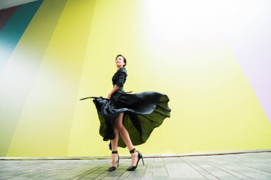 Moda kadını. Genç, güzel Çinli kız dışarıda dans ediyor uzun siyah elbiseler giyiyor ve yüksek topuklu ayakkabılar giyiyor. Modaya uygun bir bayan.. 