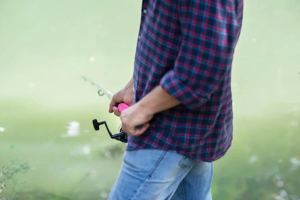 川の銀行で男釣り 夏の屋外 夏休み 釣りだ アングリング 男の手で釣り竿で光緑の湖の水の上にコピースペース — ストック写真