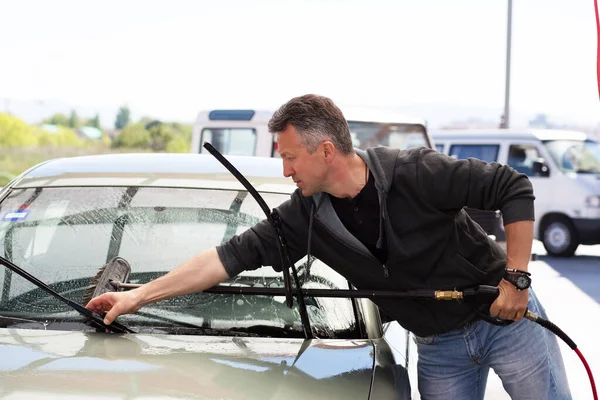 Car washing. Man cleaning car using high pressure water and brush outdoor